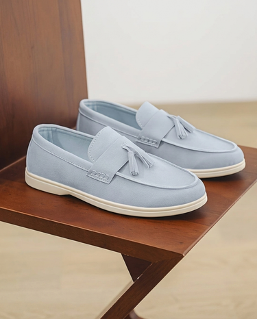 Pair of light blue loafers with tassels on a wooden surface