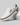 White slip-on shoe with brown accents on a gray background