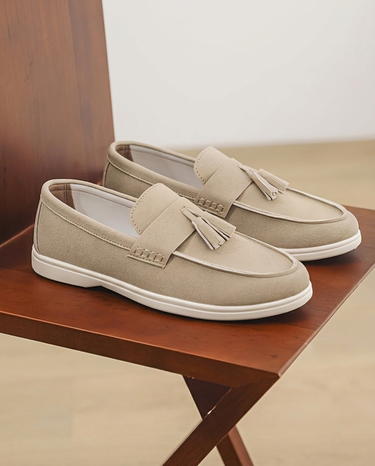 Pair of beige loafers with tassels on a wooden surface