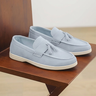 Pair of light blue loafers with tassels on a wooden surface