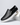 Black slip-on shoe with white sole on a light gray background
